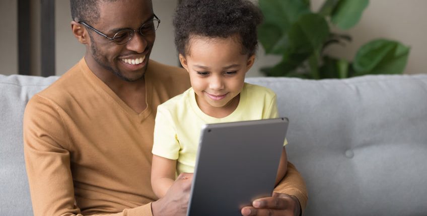 Black father teaching little son use tablet electronic device